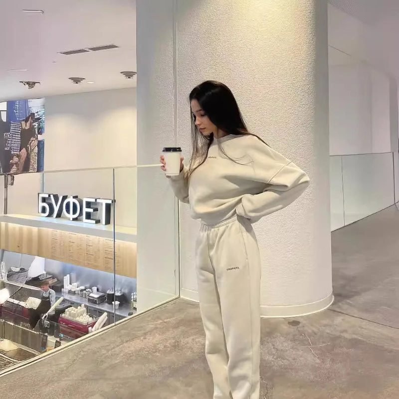 Woman in a white outfit holding a coffee cup inside a modern interior setting.