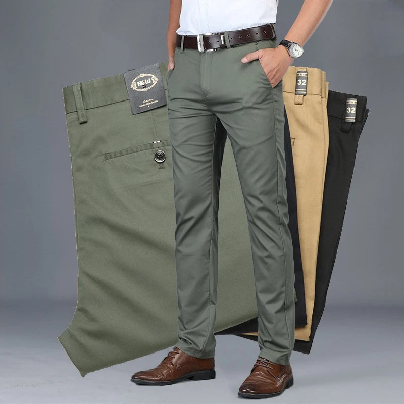 Person wearing green pants with a gray background, displaying multiple pairs of pants.