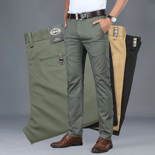 Person wearing green pants with a gray background, displaying multiple pairs of pants.