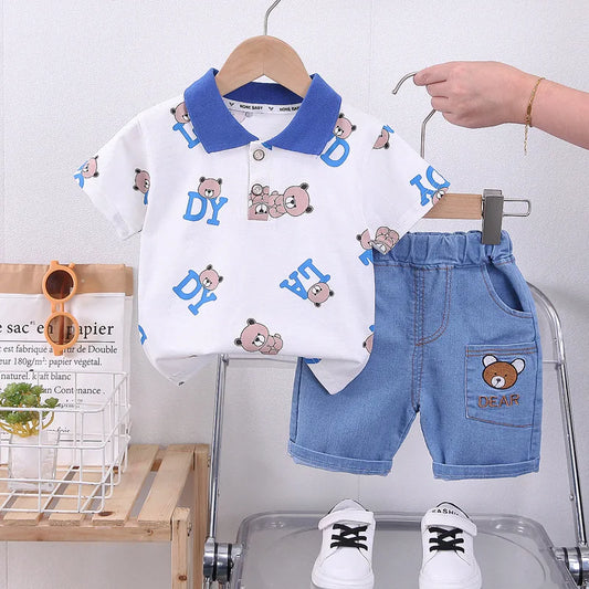 Children's outfit with white shirt and blue shorts featuring bear designs on a hanger.