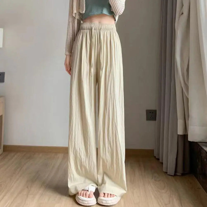 Person wearing a long beige skirt in a room with wooden flooring and neutral walls.