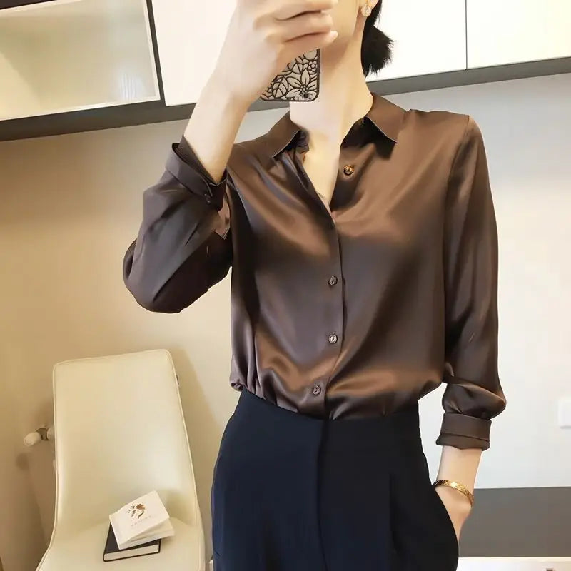 Person wearing a brown satin shirt and dark pants in an indoor setting.
