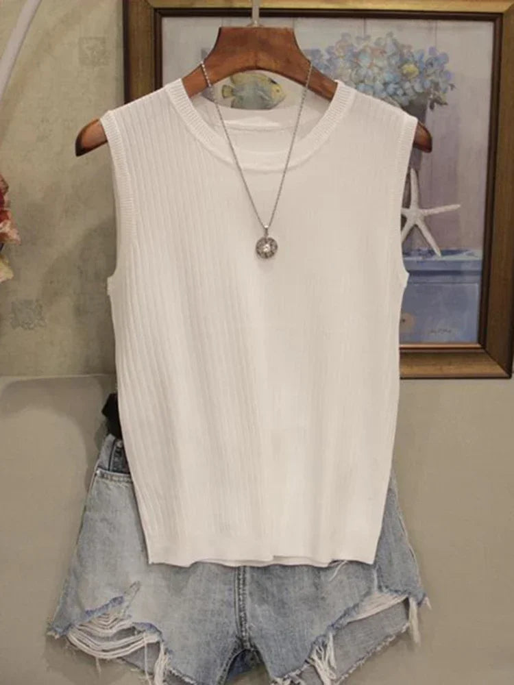 White sleeveless top on a hanger with denim shorts below, against a neutral background.