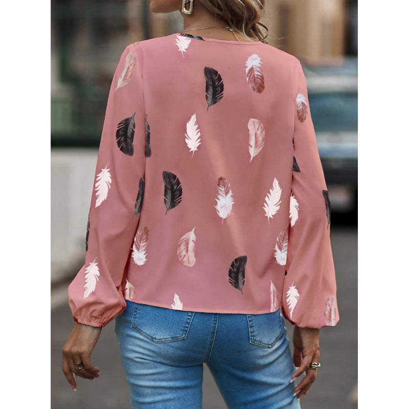 Pink blouse with feather pattern worn by a person, blurred background