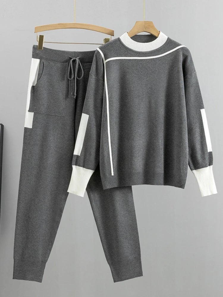 Gray tracksuit with white accents on hangers against a gray background