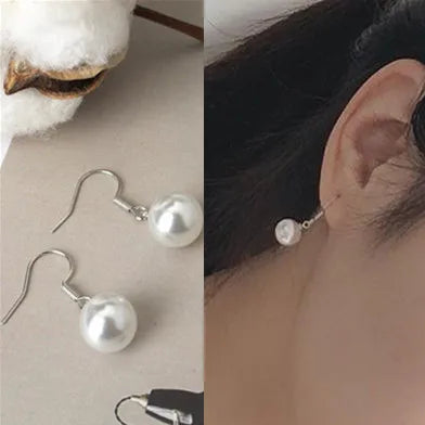 Pearl earrings displayed on a neutral background with an ear wearing one of the earrings.