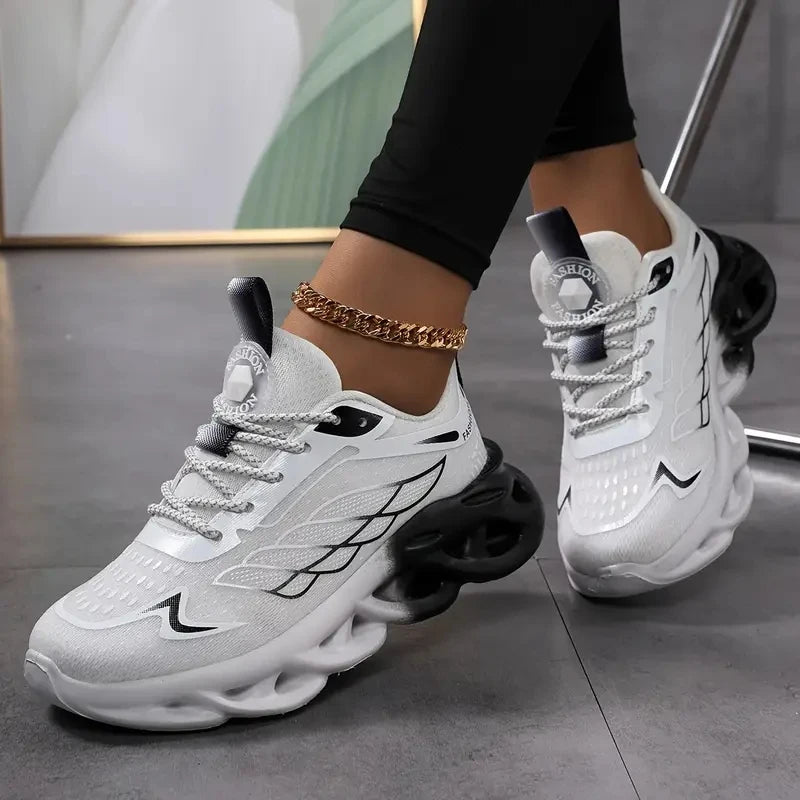 White sneakers with black accents worn by a person on a gray floor.