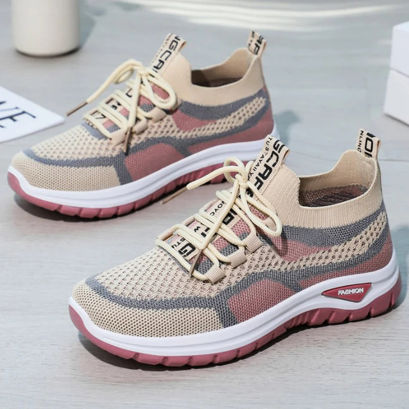Pair of beige and red sneakers on a light gray surface