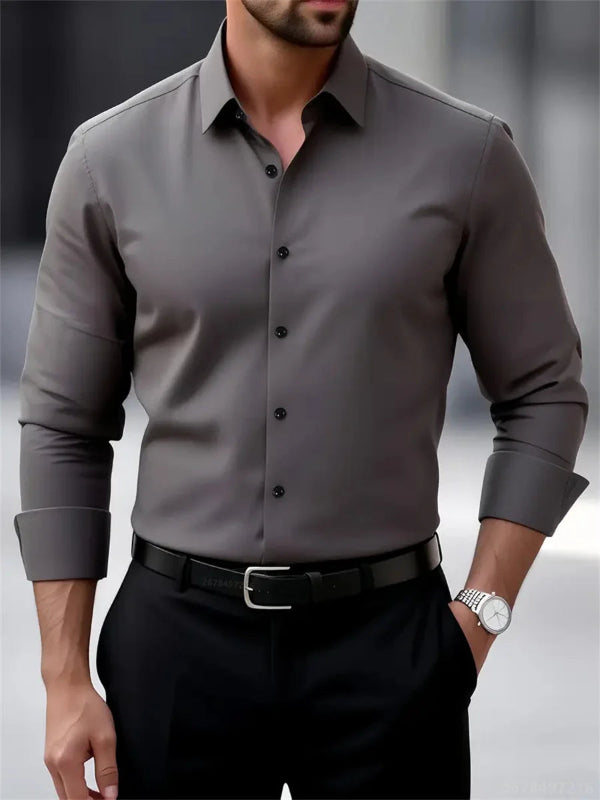 Man wearing a gray dress shirt with rolled-up sleeves and black pants.