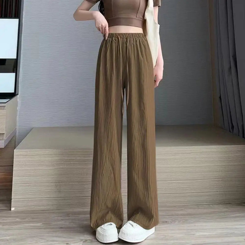 Person wearing brown wide-leg pants and a matching top in a minimalistic room.
