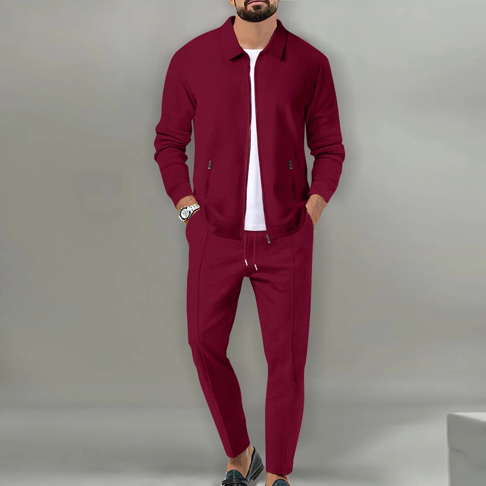 Man wearing a burgundy tracksuit against a gray background