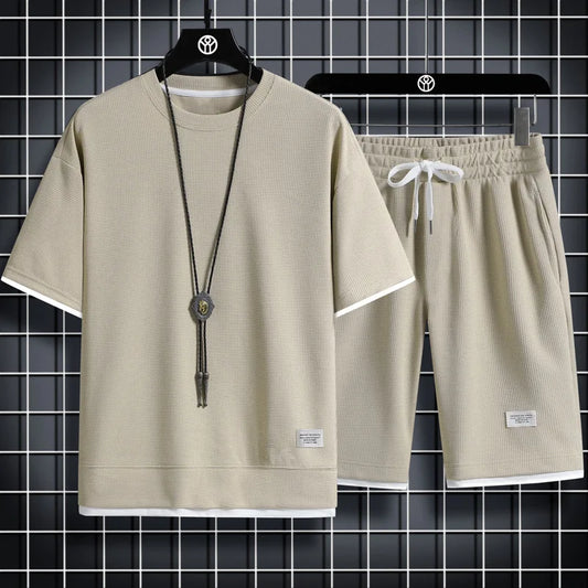 Beige t-shirt and shorts set on hangers against a tiled wall background