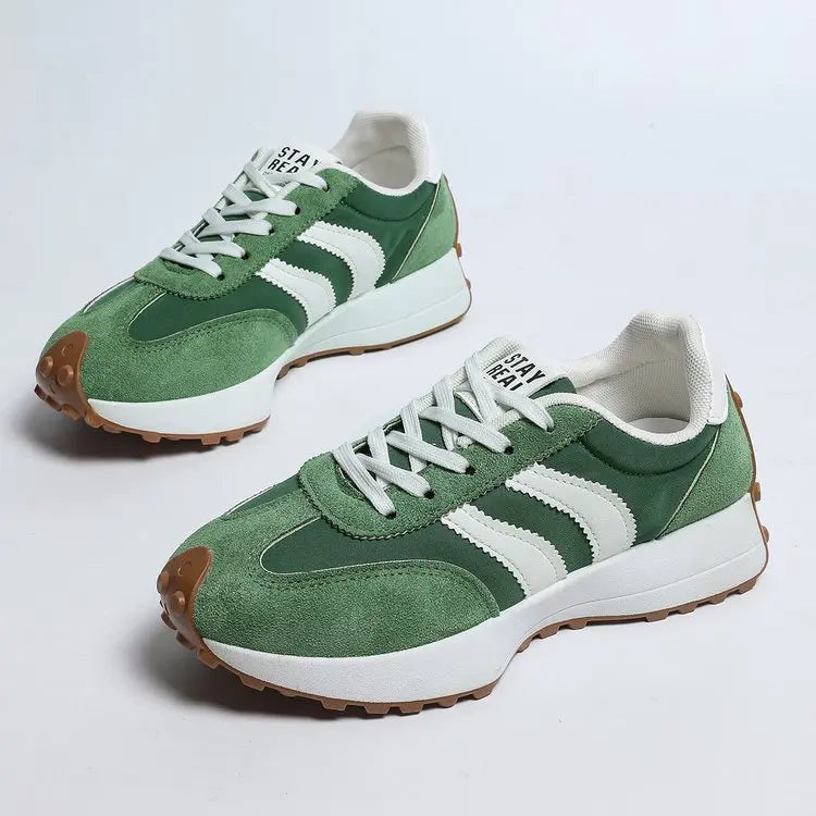 Green and white sneakers with brown soles on a light gray background