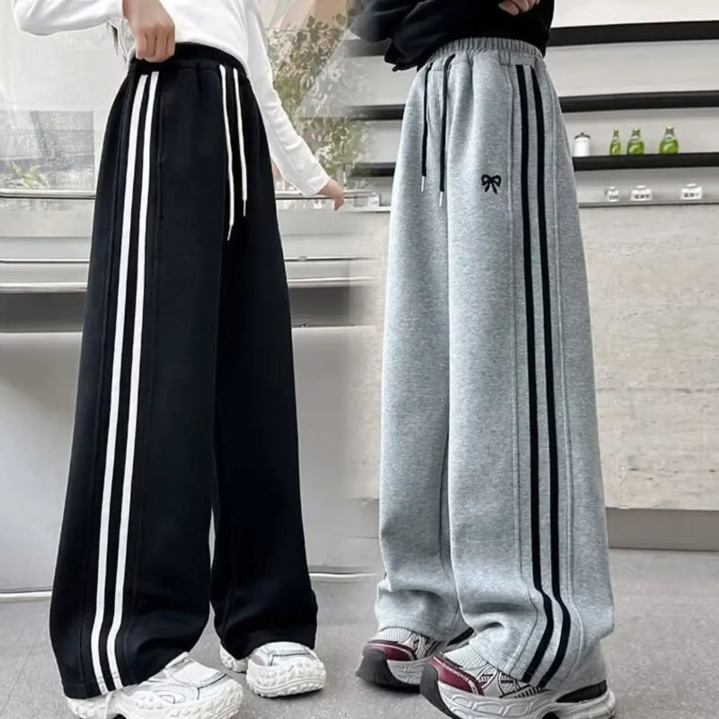 Two pairs of wide-leg pants with stripes worn by people indoors.