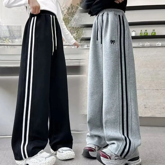 Two pairs of wide-leg pants with stripes worn by people indoors.