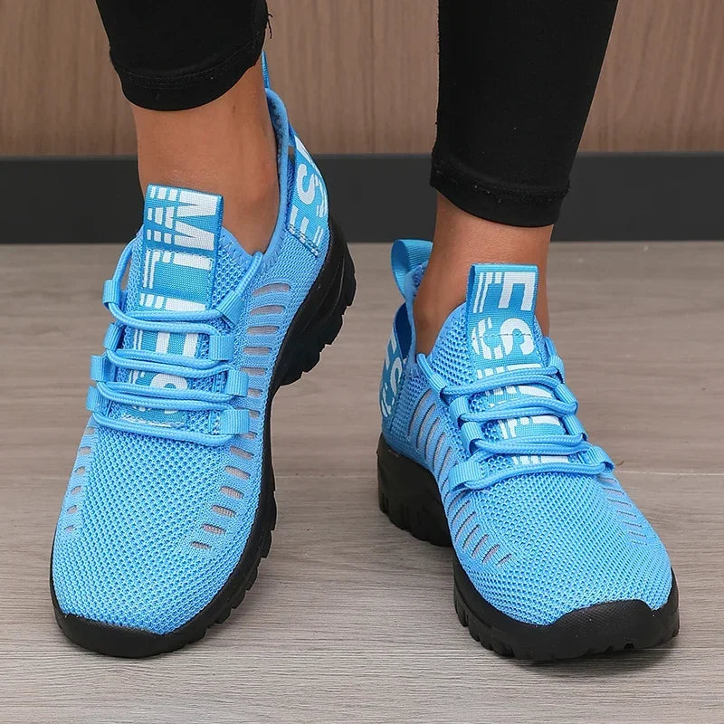 Blue athletic shoes with black soles on a wooden floor