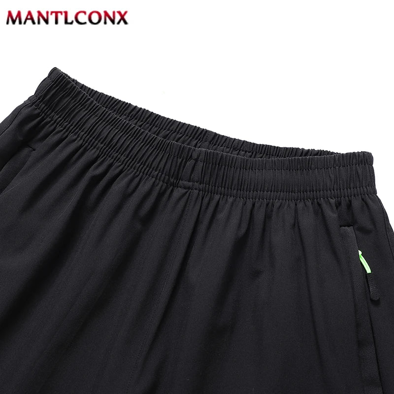 Black shorts with a green zipper tag on a white background, featuring the brand 'MANTLCONX'.