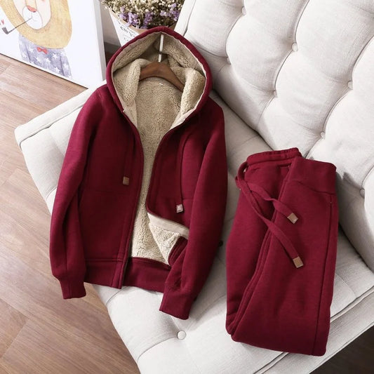 Red hoodie and pants on a white couch with a wooden floor and plant in the background