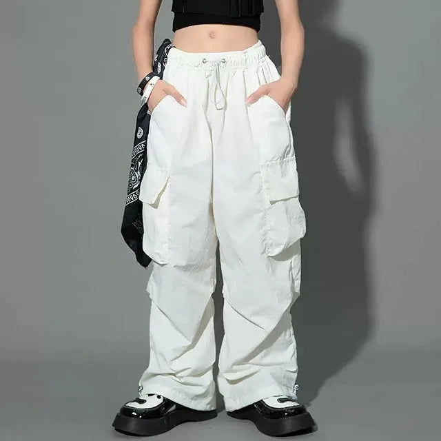 Person wearing white cargo pants on a gray background