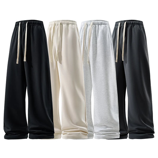 Four pairs of sweatpants in black, white, gray, and dark gray on a white background.