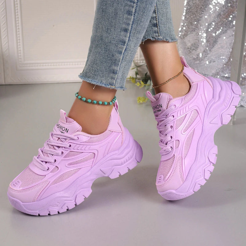 Purple sneakers worn with light blue jeans on a neutral background