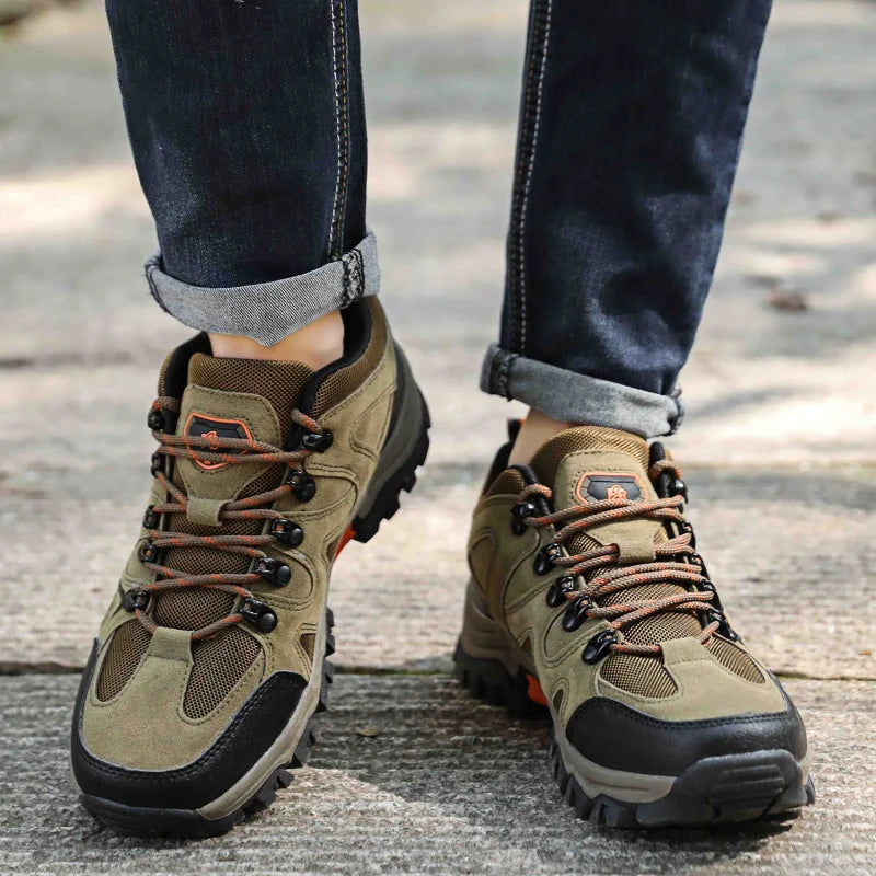 Brown hiking boots with black soles worn by a person on a wooden floor.