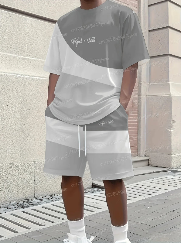 Person wearing a gray and white outfit with brand logos, standing against a building.