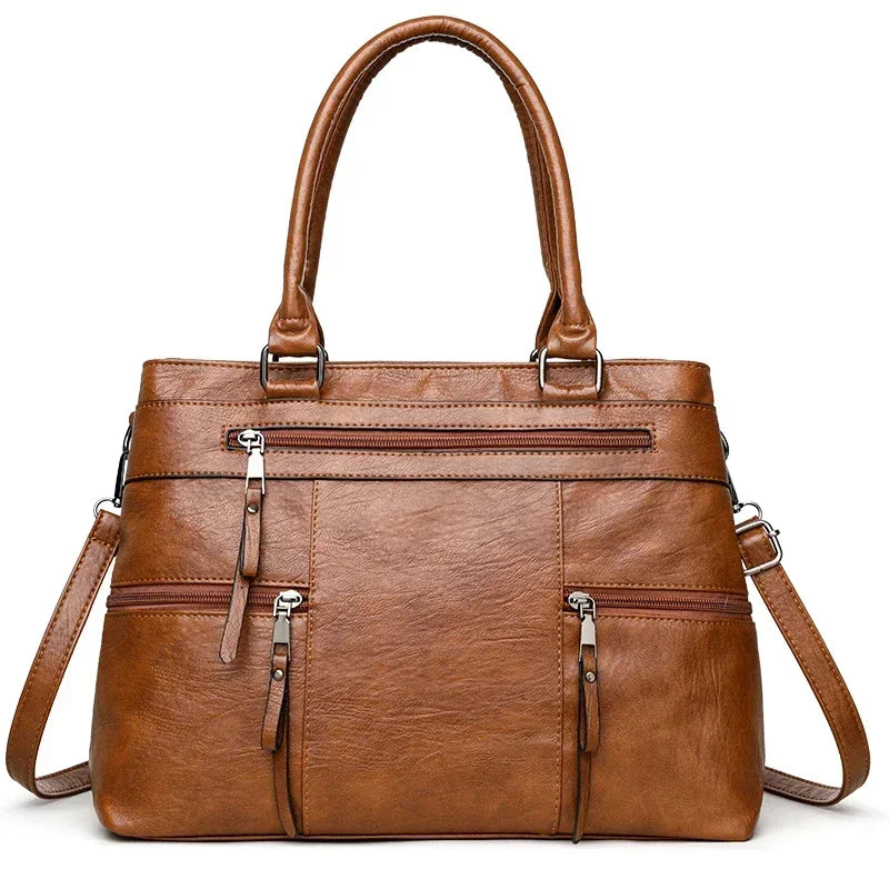 Brown leather handbag with multiple pockets and zippers on a white background