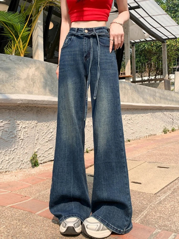 Person wearing blue wide-leg jeans and a red top outdoors.