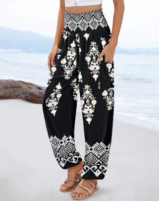 Black pants with white floral patterns worn by a person on a beach.