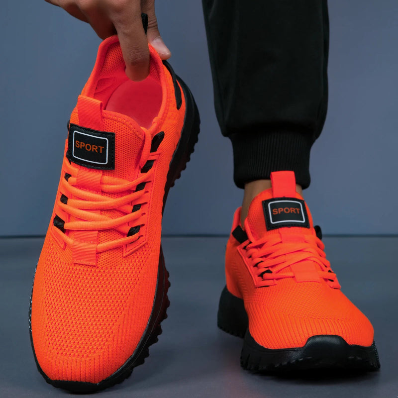 Orange sneakers with black soles and 'Sport' label on a dark background