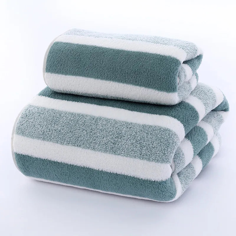 Two striped towels, one green and white, the other blue and white, on a light gray background.