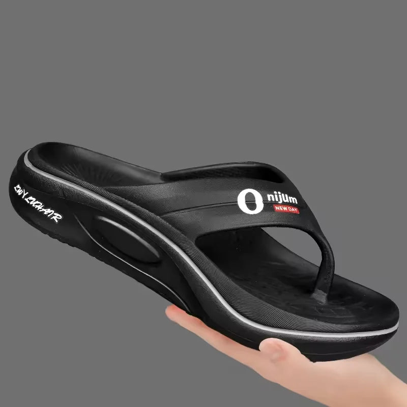 Black sandal with a brand logo held by a hand on a gray background