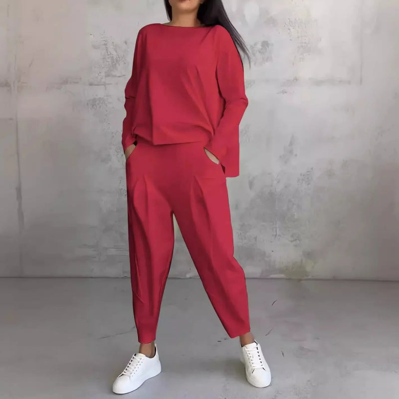 Person wearing a red outfit with white sneakers against a gray concrete wall.