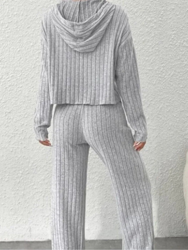 Person wearing a gray ribbed knit outfit against a white wall