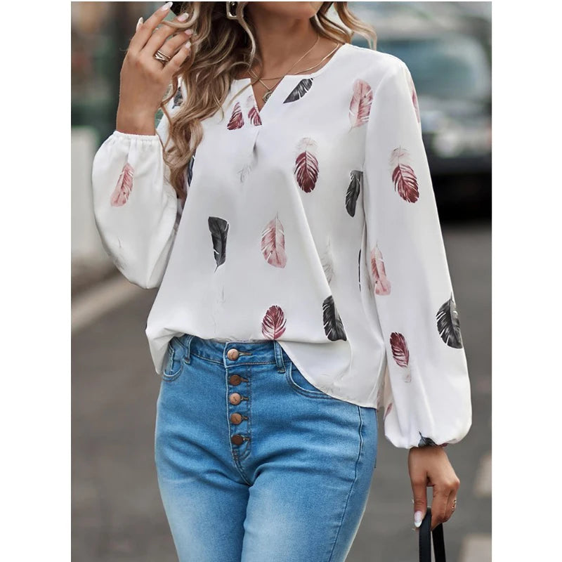 White blouse with feather pattern and blue jeans worn by a person.