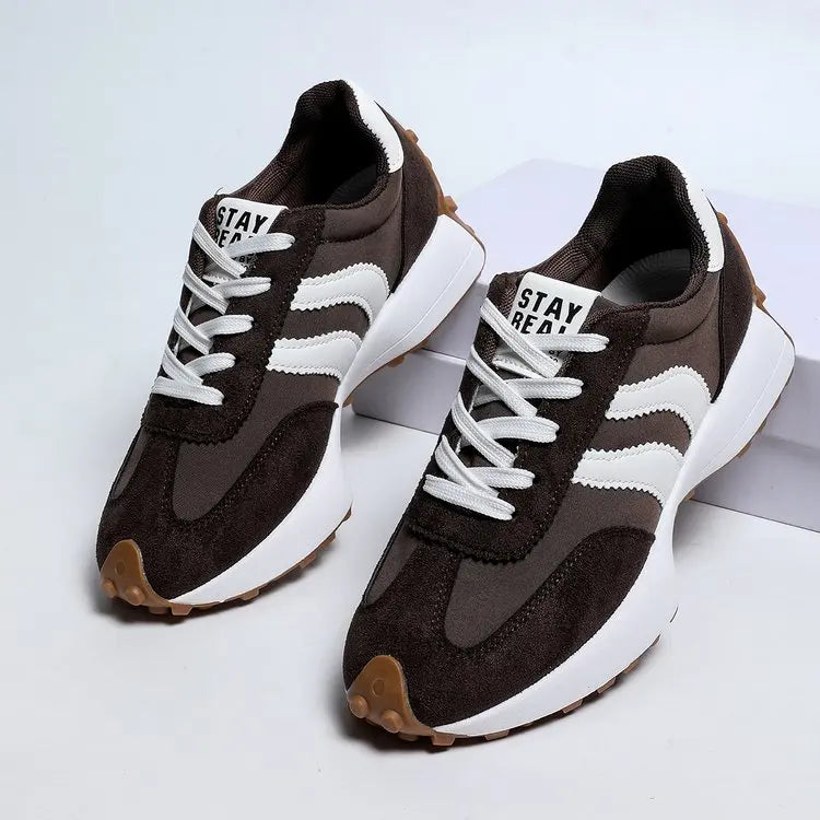 Pair of brown and white sneakers on a light gray background