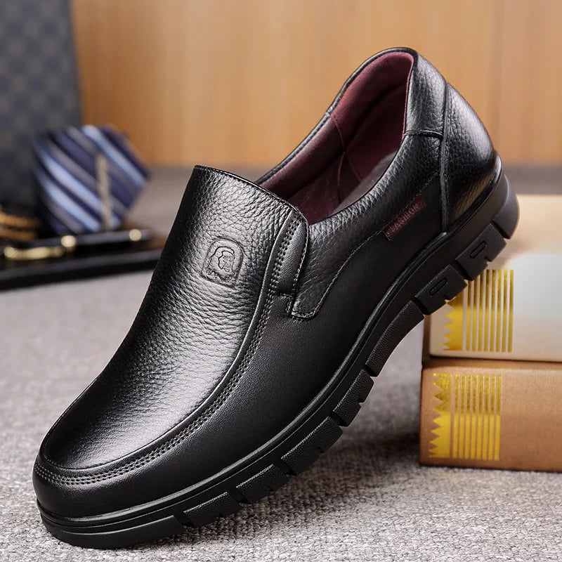 Black leather shoe on a textured surface with books and a tie in the background