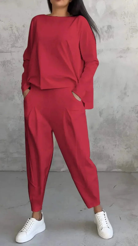 Person wearing a red outfit with white sneakers against a gray concrete wall.
