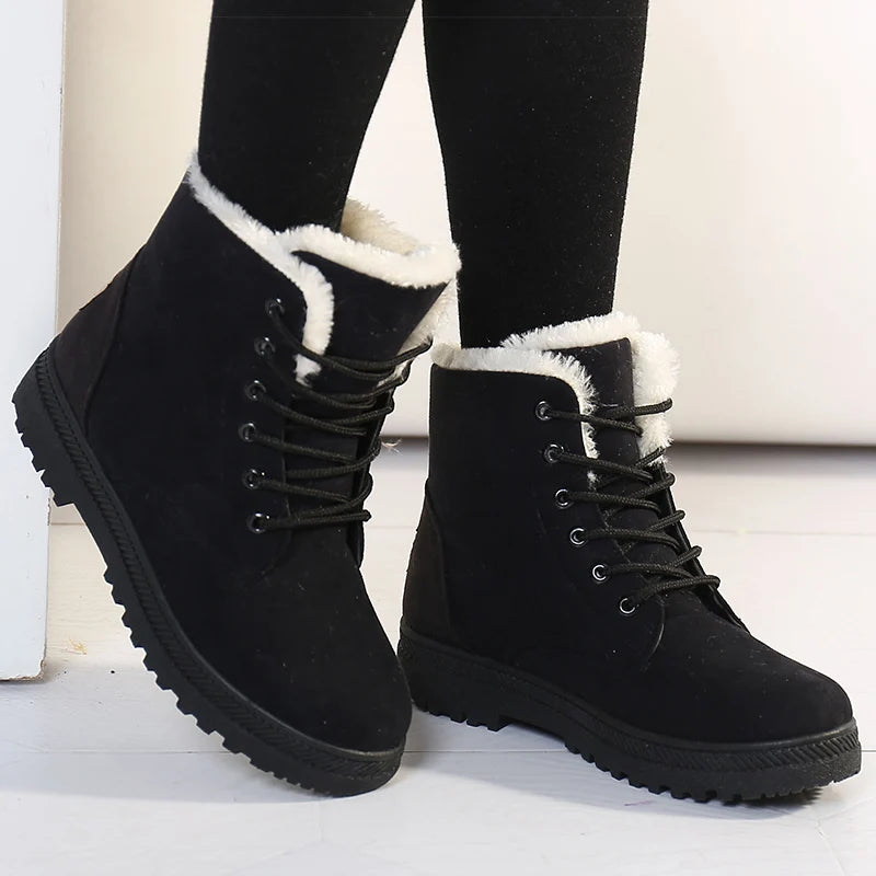 Black winter boots with white fur lining worn by a person on a light background