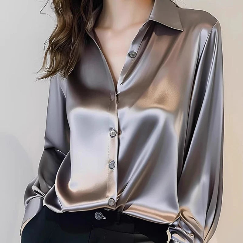 Silky silver blouse worn by a person on a plain background