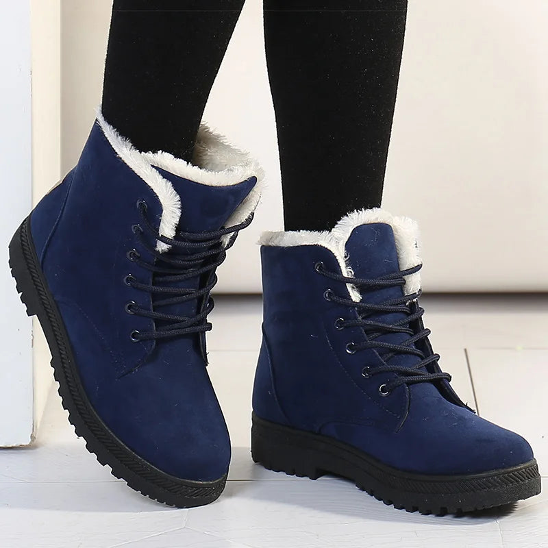Blue winter boots with white fur lining worn by a person on a light background
