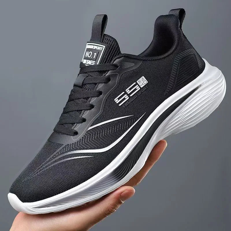 Black running shoe with white sole held in a hand against a gray background