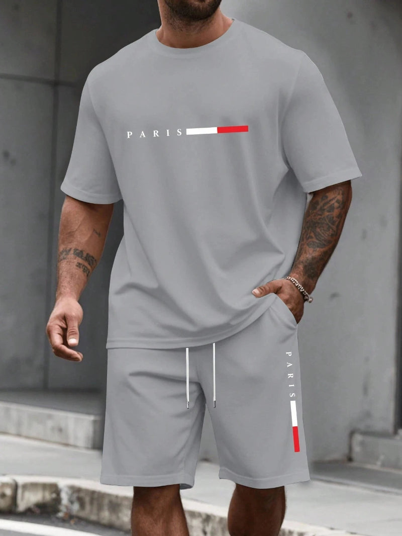 Person wearing a gray 'PARIS' t-shirt and shorts set with visible tattoos.