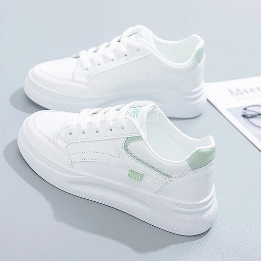 White sneakers with green accents on a light gray surface