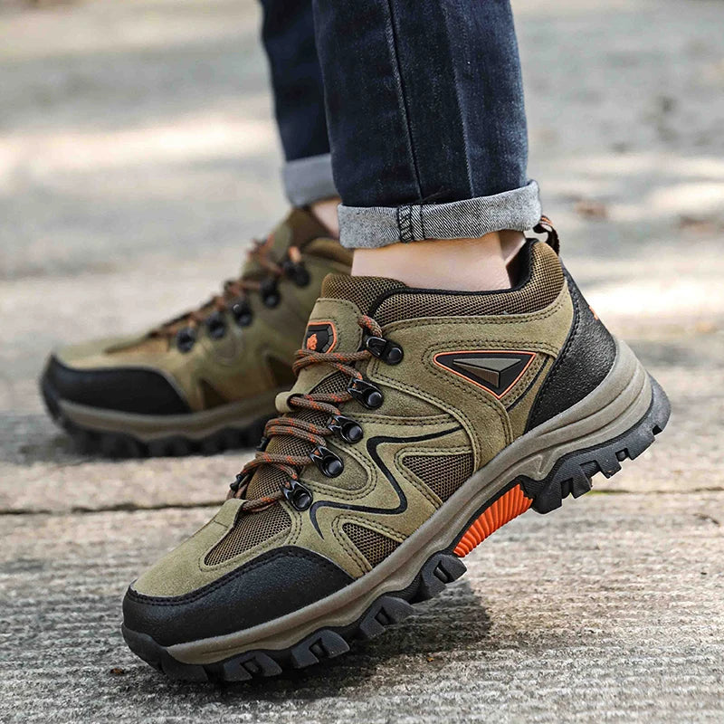 Brown hiking boots with orange accents worn by a person on a blurred outdoor background