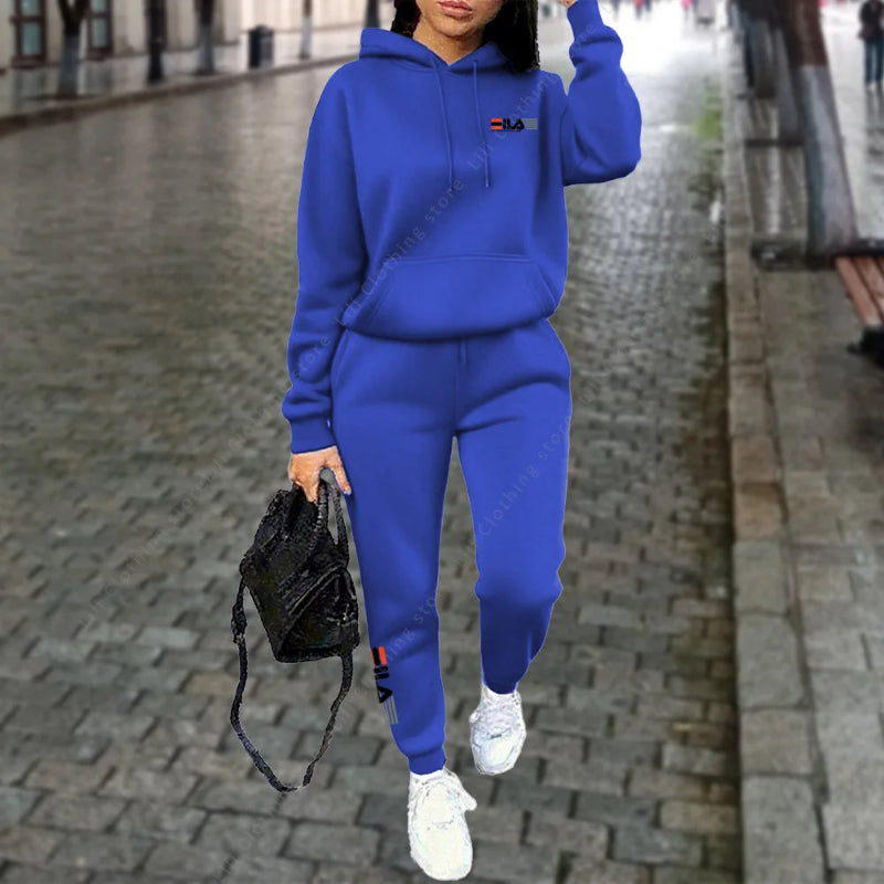 Person wearing a blue tracksuit with a brand logo on a city street.