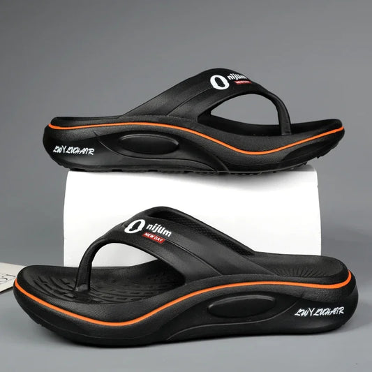 Black sandals with orange accents on a gray background