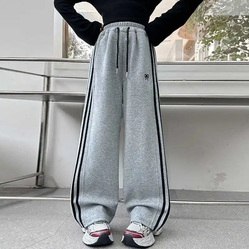 Person wearing gray sweatpants with black stripes indoors.