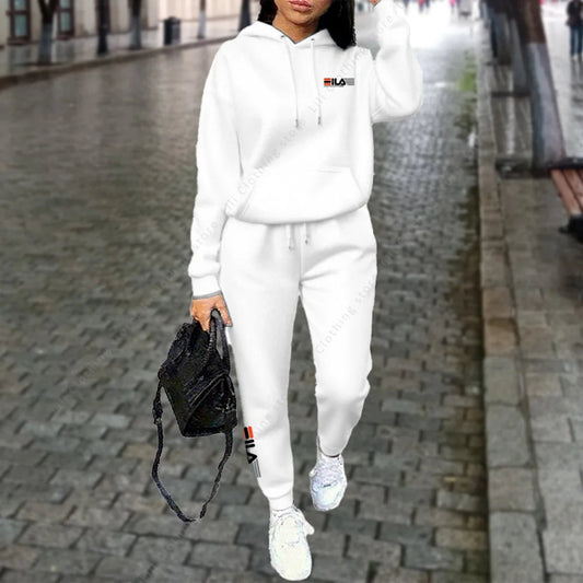 Person wearing a white tracksuit with a brand logo on a city street.